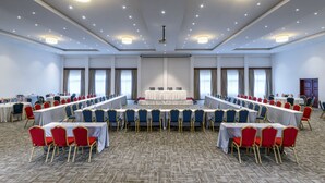 Un salón de conferencias con una larga mesa y sillas, un proyector y una pantalla.