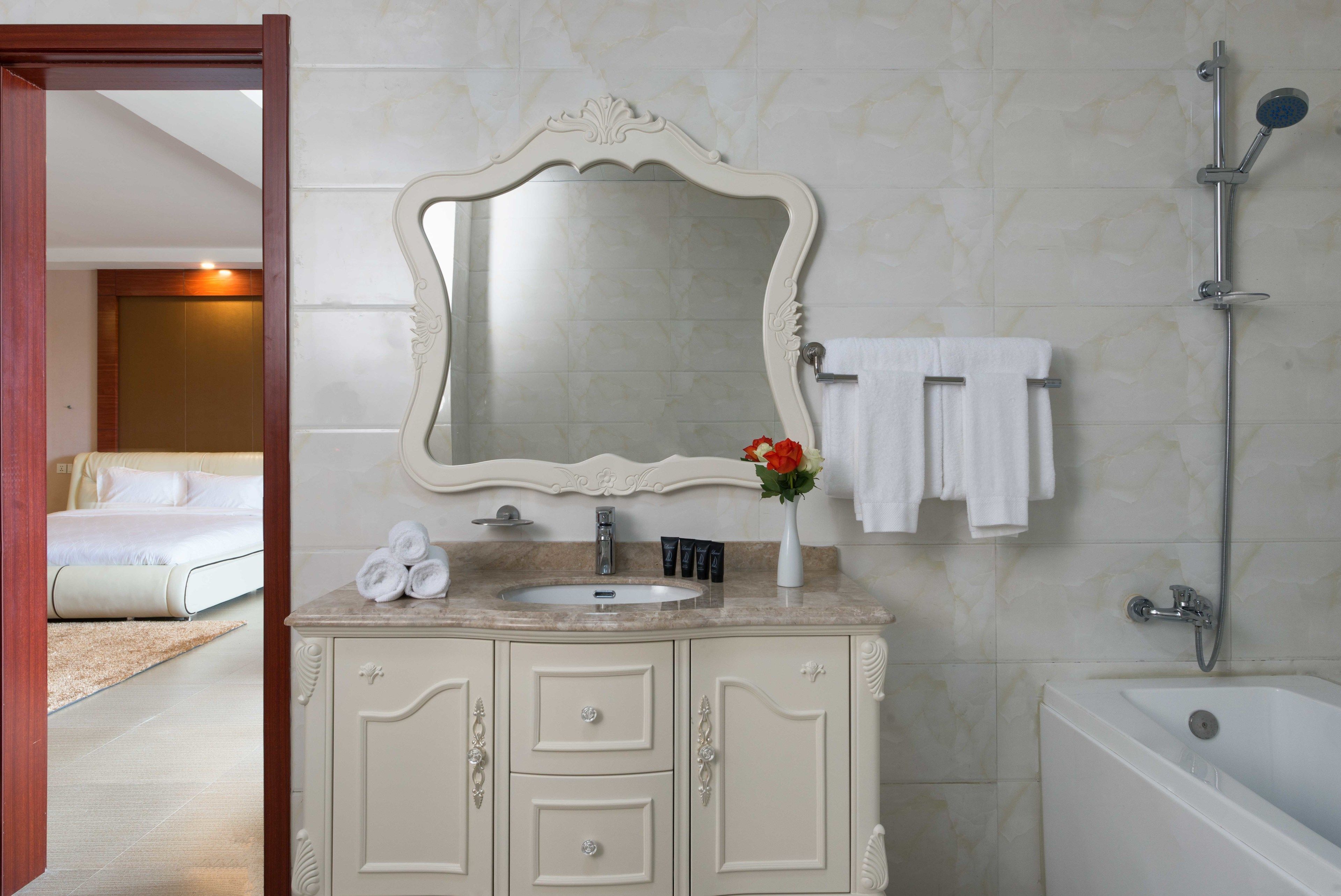 A bathroom with a sink, mirror, and shower.