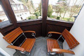 A corner balcony with two wooden benches and a view of a residential area.