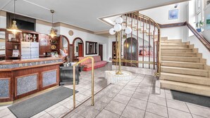 Ein Hotel-Empfangsbereich mit Empfangstresen, einer Treppe und einer Sitzecke.