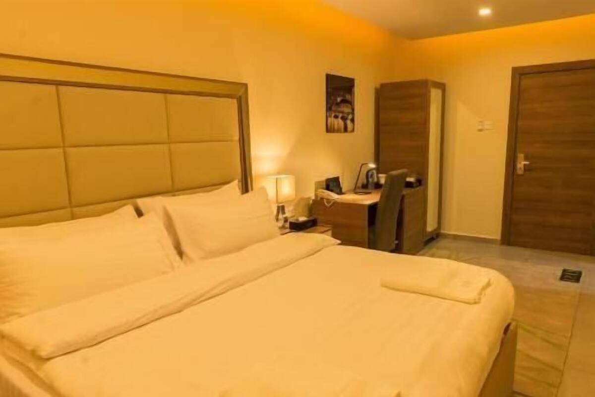 A hotel room with a bed, bedside table, lamp, and a wardrobe.