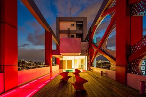 A rooftop terrace with a view of the city skyline, featuring a modern architectural design with red and white color scheme. - Hotel Poispois (Taipei)