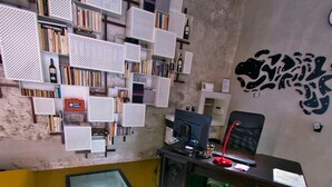 Una habitación con escritorio, silla, estantería y espejo.