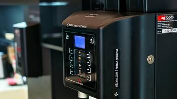 A commercial coffee machine with a digital interface, a water tank, and a coffee dispensing area.