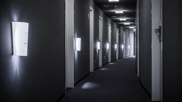 A long, narrow hallway with doors on both sides, illuminated by overhead lights.