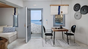 A compact room with a view of the sea, a dining area with a table and chairs, and a cozy seating area with a patterned pillow. - Chrysalis Boutique Hotel (Astypalaia)