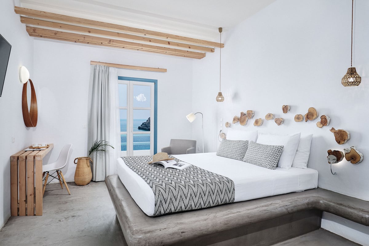 Un dormitorio moderno con una cama grande, un escritorio y vistas al mar.
