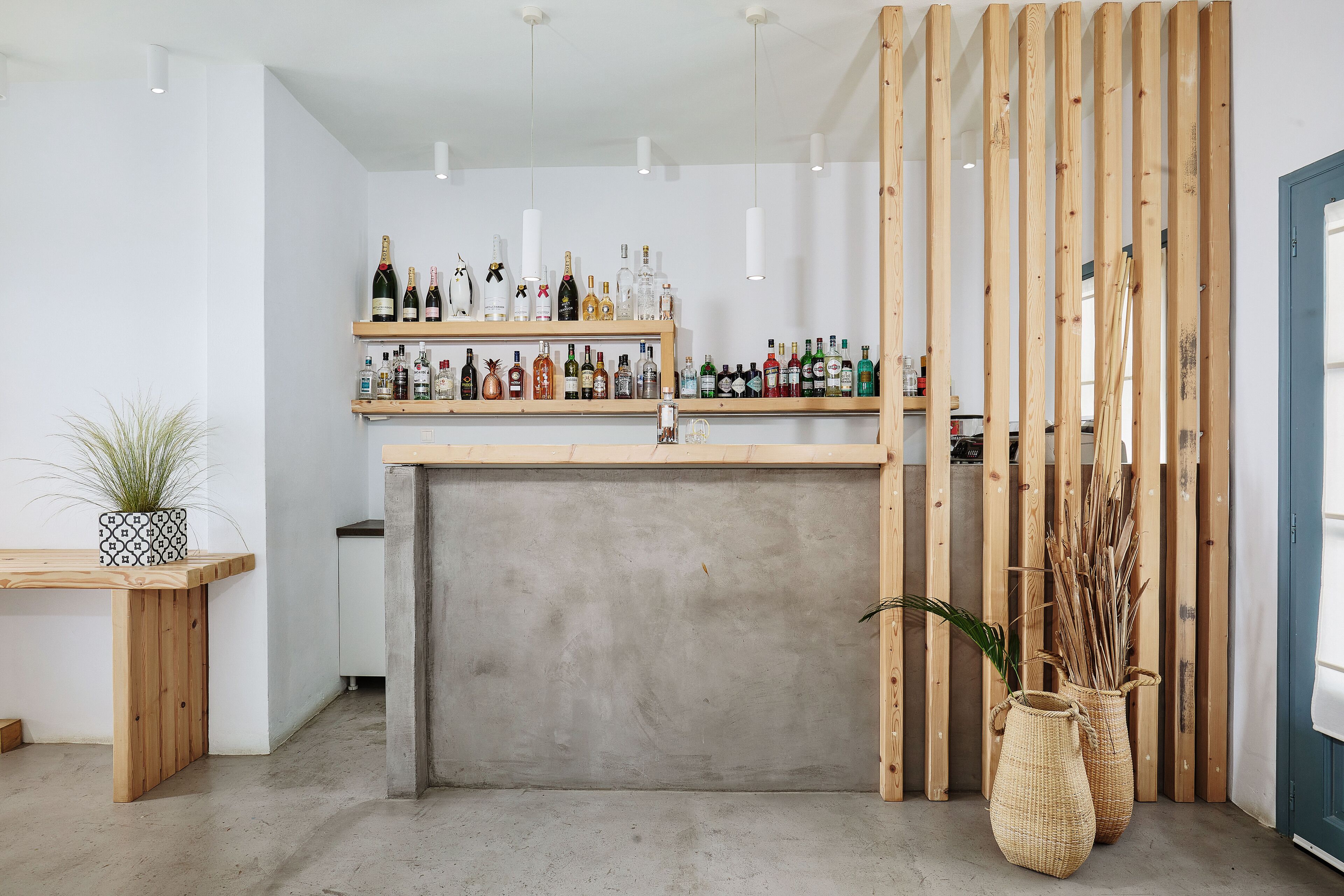 A bar area with shelves of various liquor bottles, a concrete counter, and wooden slats.