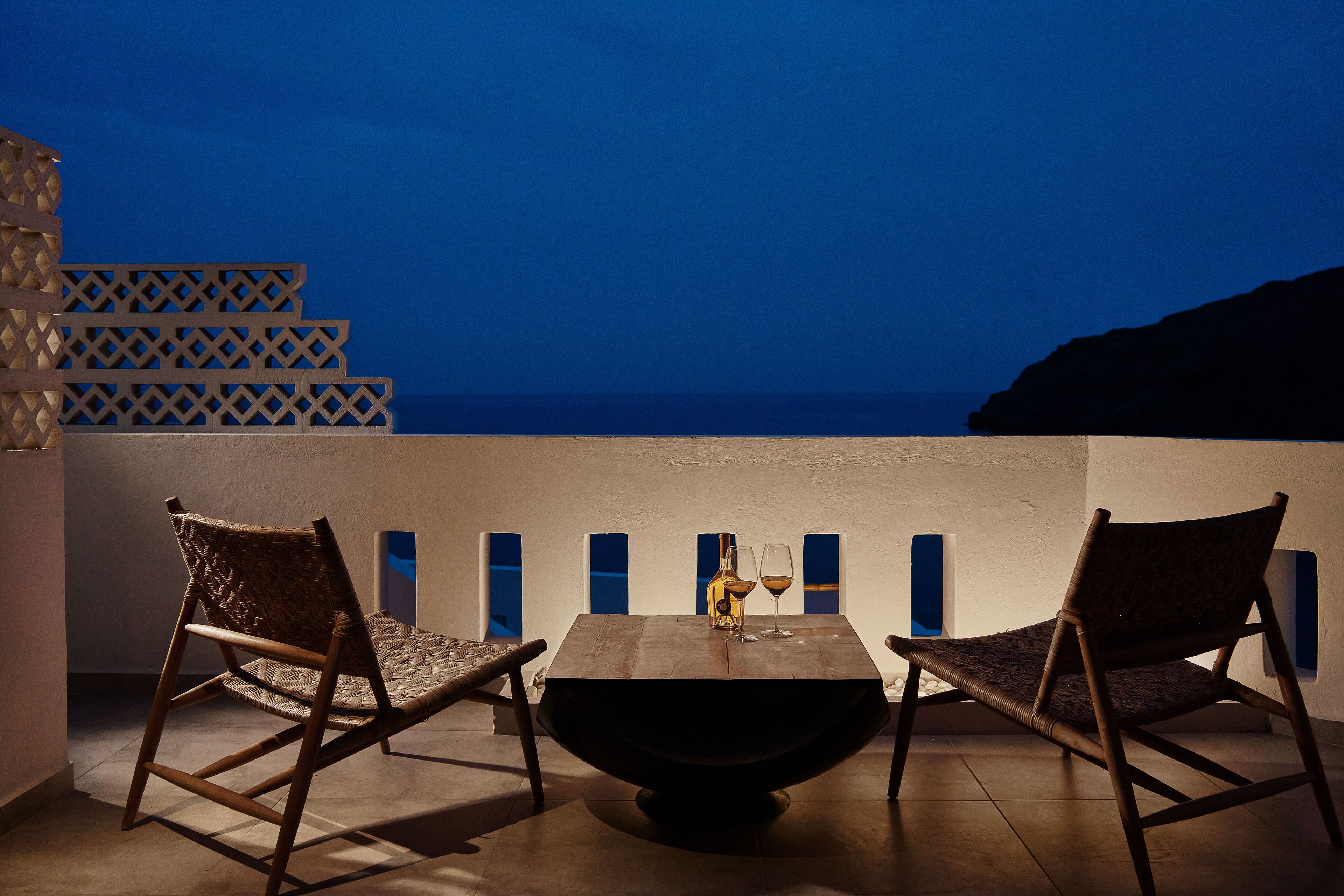 A dining area with a table and two chairs, a bottle, and a glass on the table.