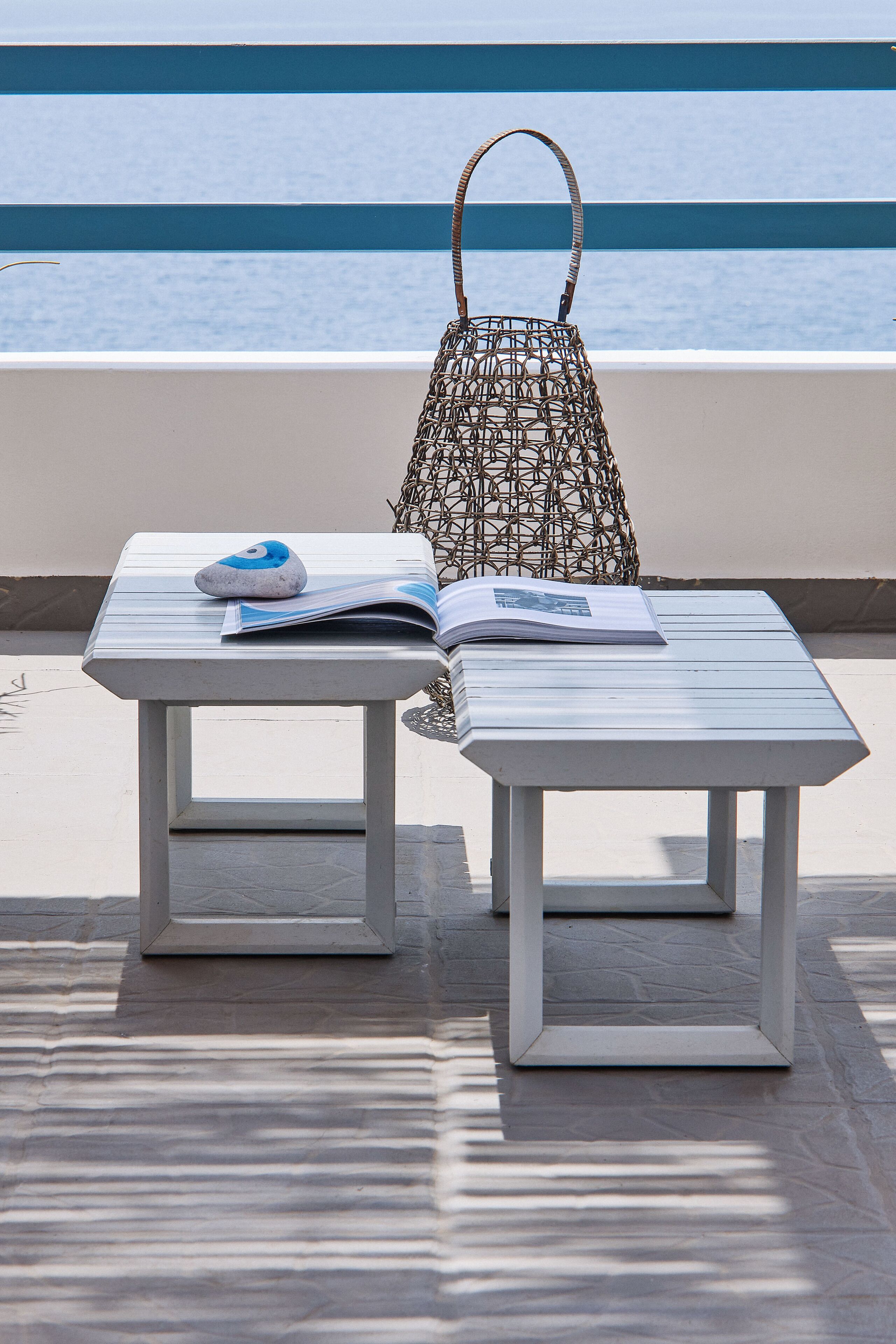 A lounge area with a table and chairs, a woven bag, and a magazine.