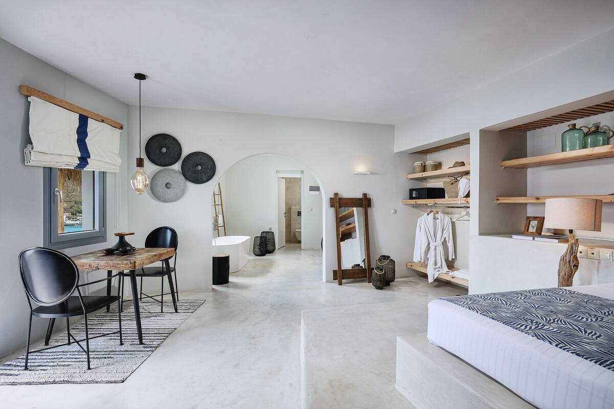 Un dormitorio moderno con una cama grande, un escritorio de madera y un rincón de comedor.
