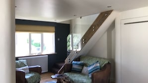 Un salón estilo loft con techo alto, una escalera y un ventanal grande.