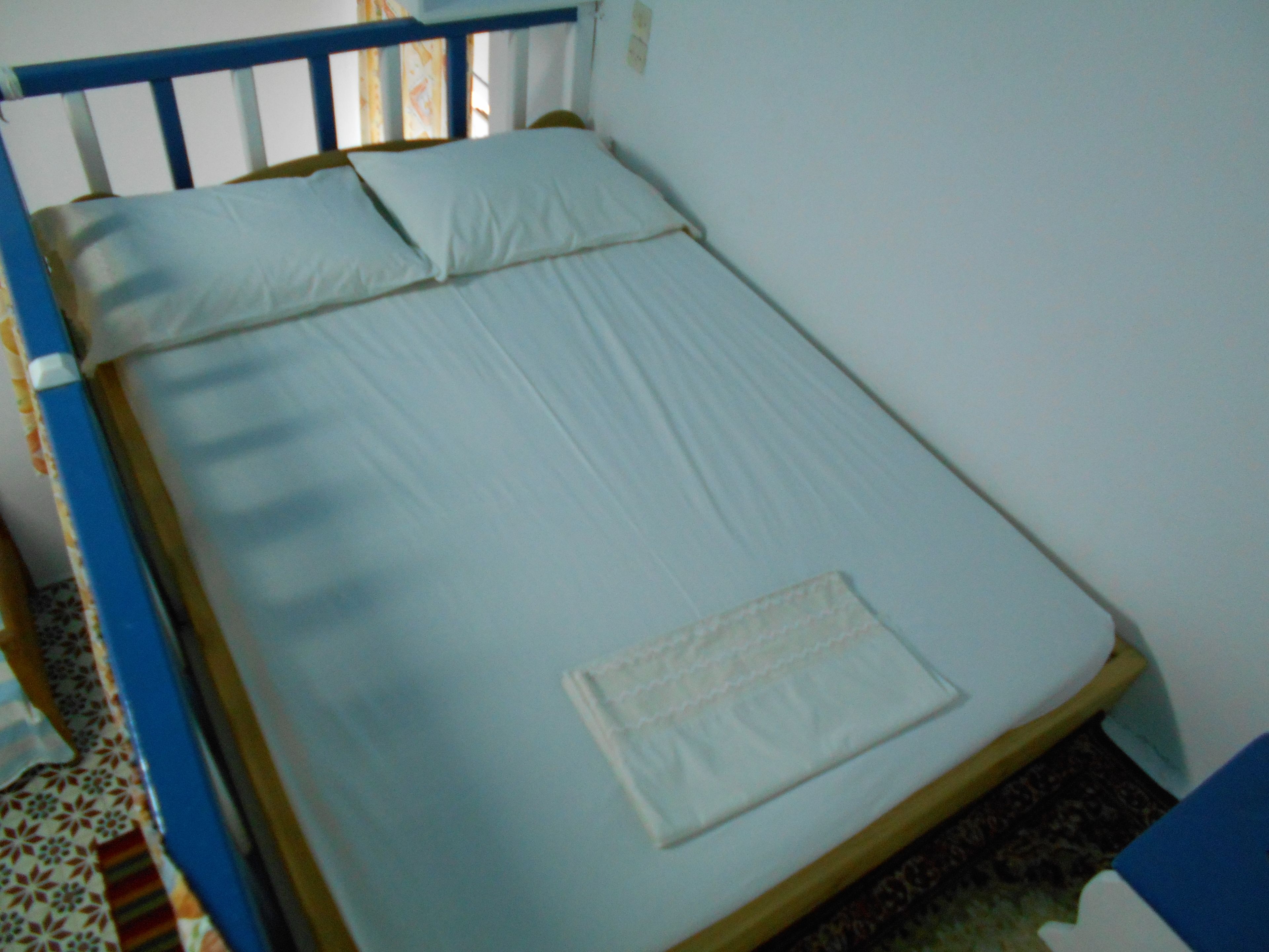 A single bed with a wooden frame and a white mattress.