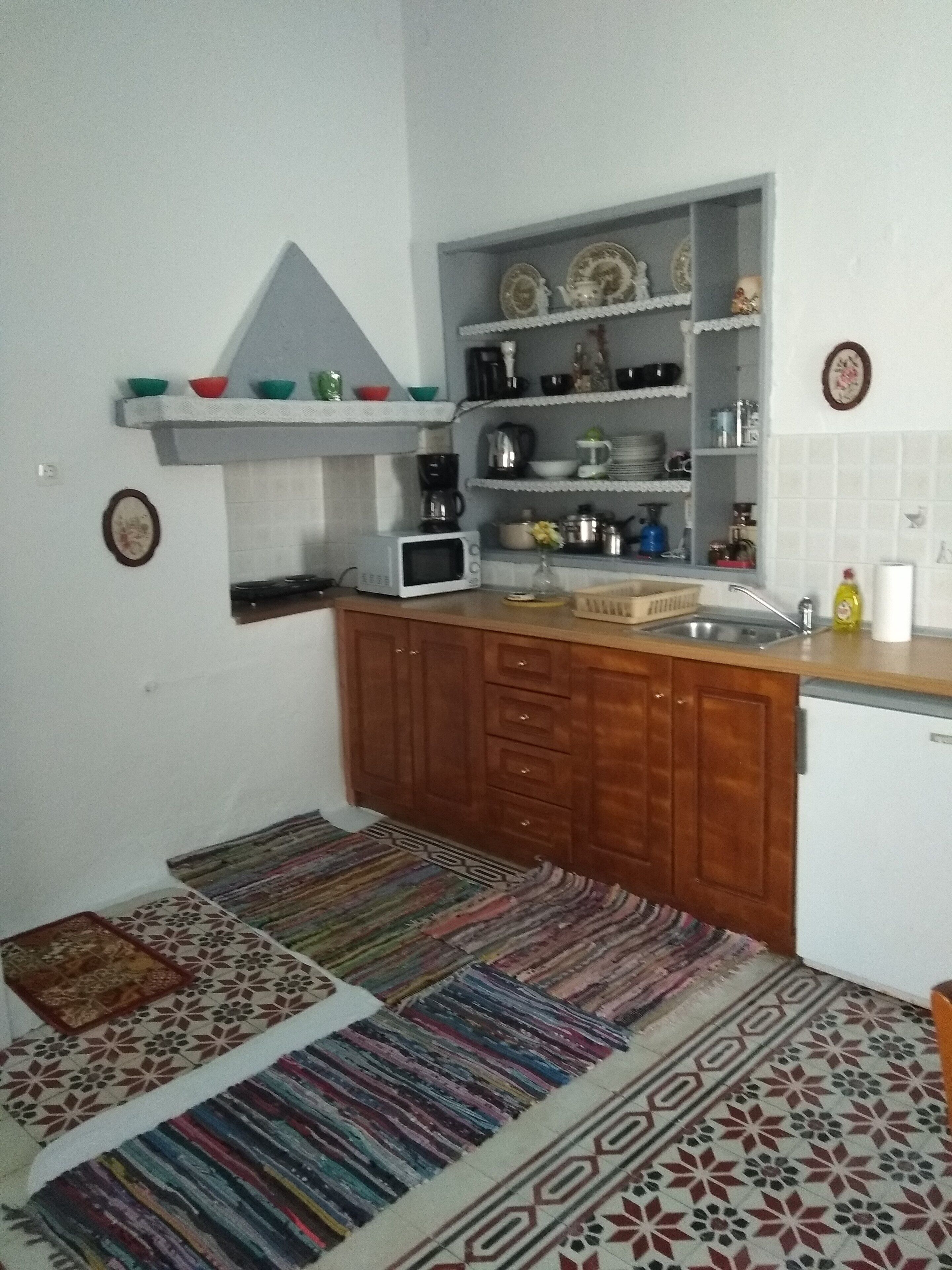 Een kleine keuken met houten kastjes, een magnetron en een spoelbak.
