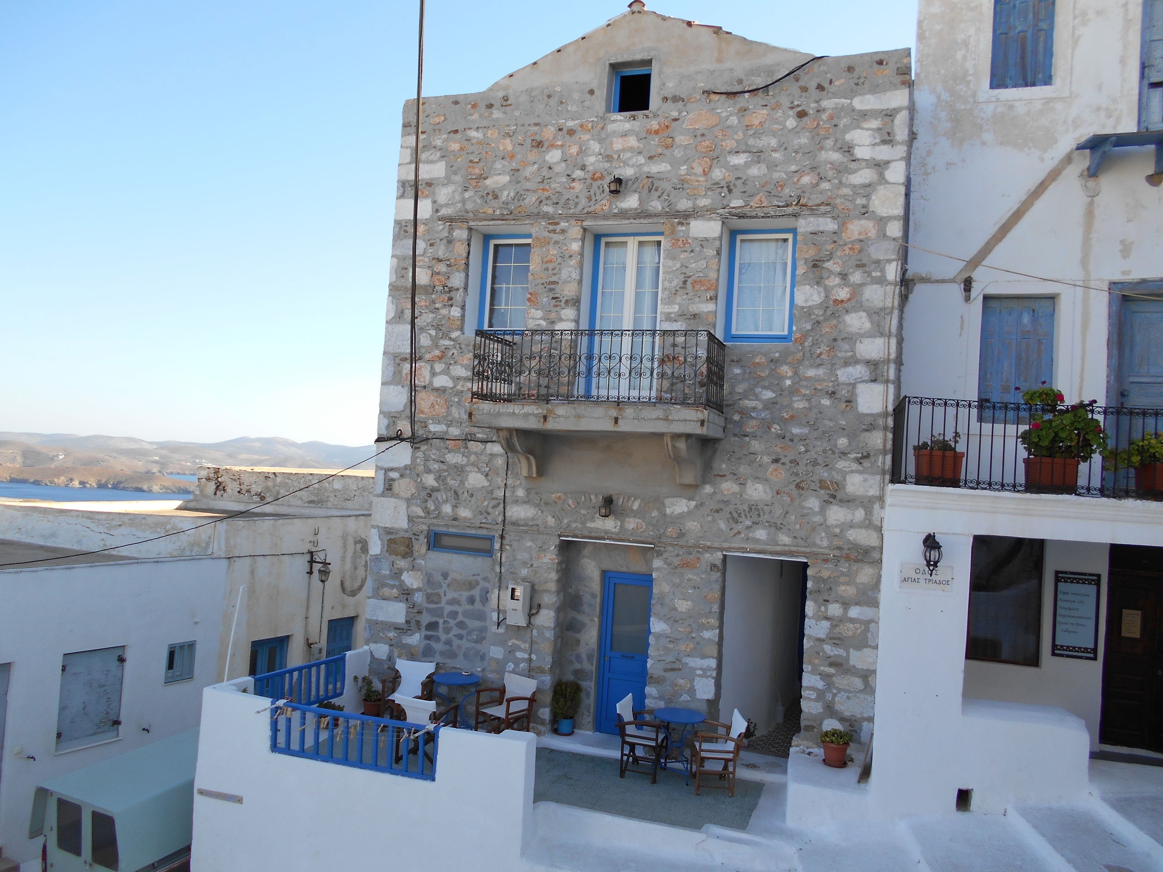 Un edificio de piedra de dos pisos con contraventanas azules y un balcón.