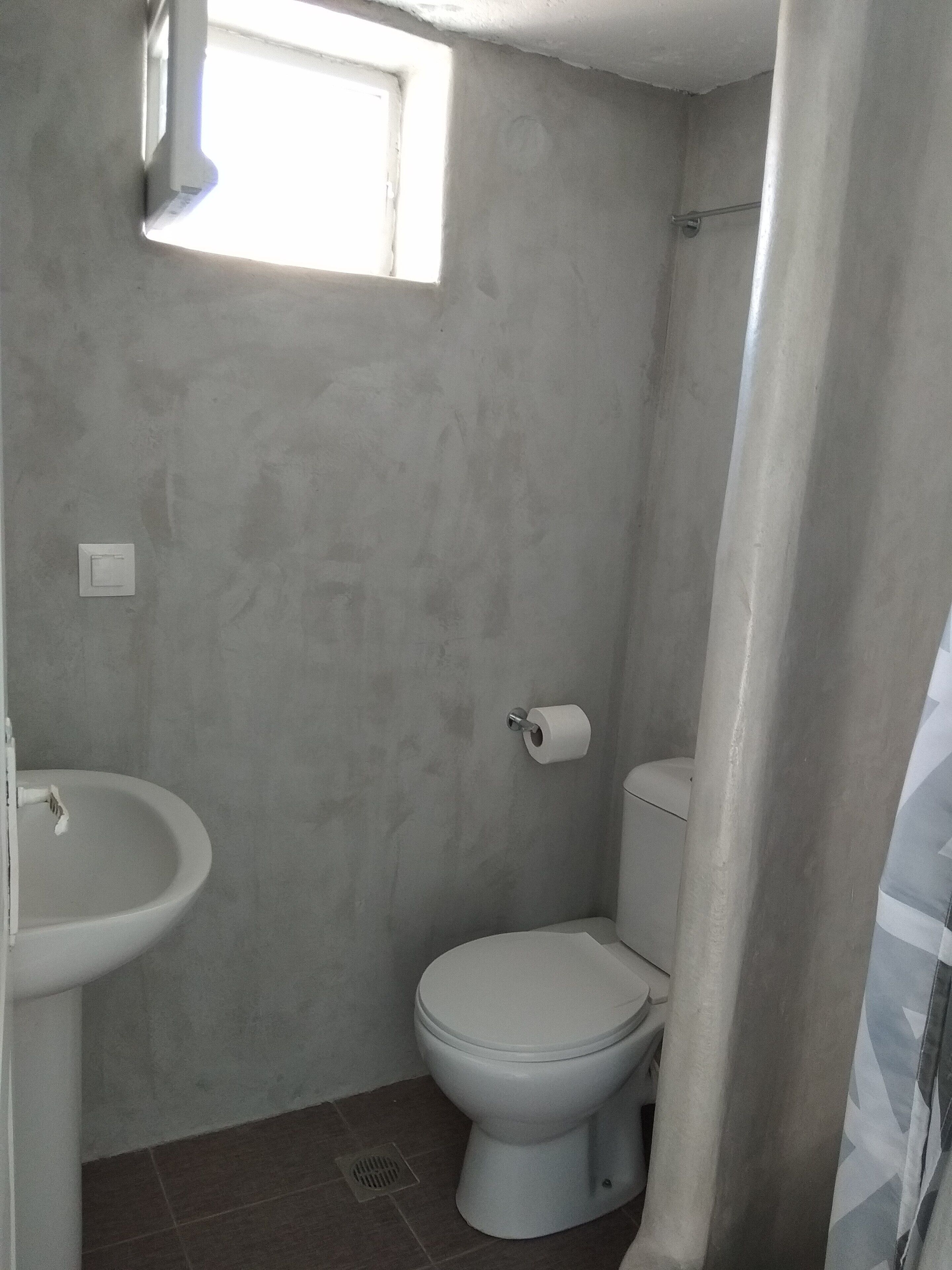 A bathroom with a toilet, sink, and a window.