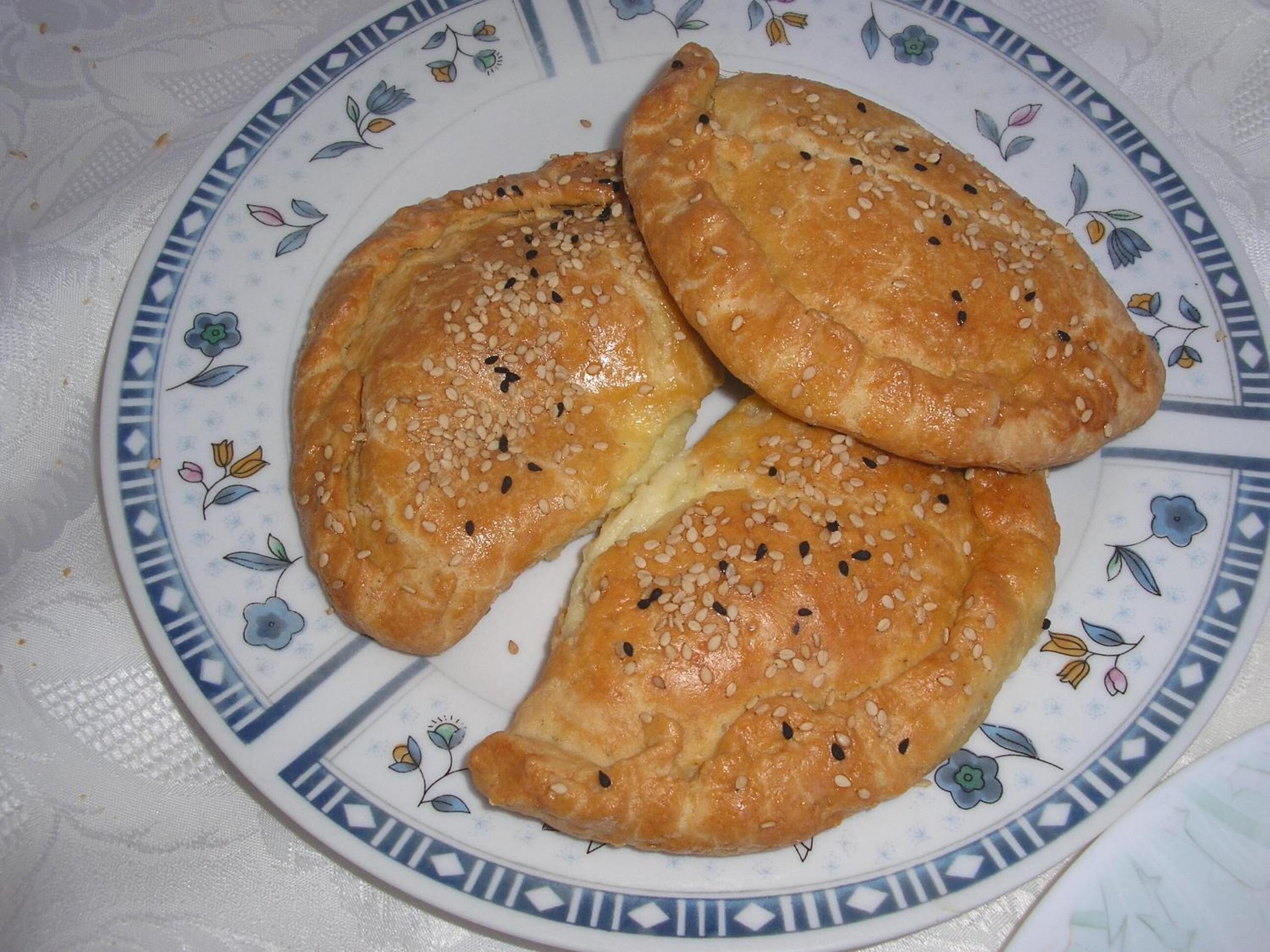 Three golden-brown pastries on a decorative plate with a floral pattern.