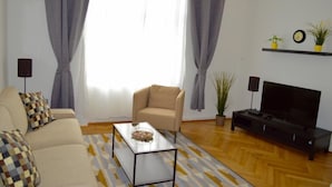 A living room with a sofa, a coffee table, a TV stand, and a potted plant. - Sweet Living Naschmarkt (Vienna)