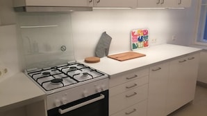 A modern kitchen with a gas stove, oven, and white cabinetry. - Sweet Living Naschmarkt (Vienna)