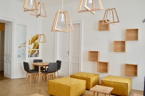 Un comedor moderno con sillas de madera, una mesa redonda y otomanas amarillas.