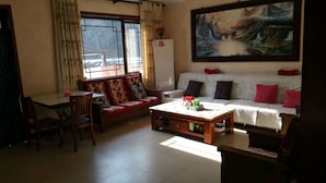 A living room with a sofa, a coffee table, and a dining table with chairs. - Beijing Ju Man Yuan Triditional Hotel (Miyun)