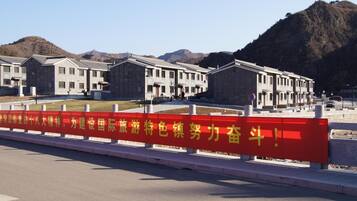 A building with a red barrier in front, a clear sky, and mountains in the background.