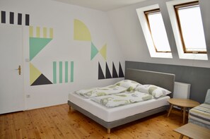 A bedroom with a bed, a small table, and a window.