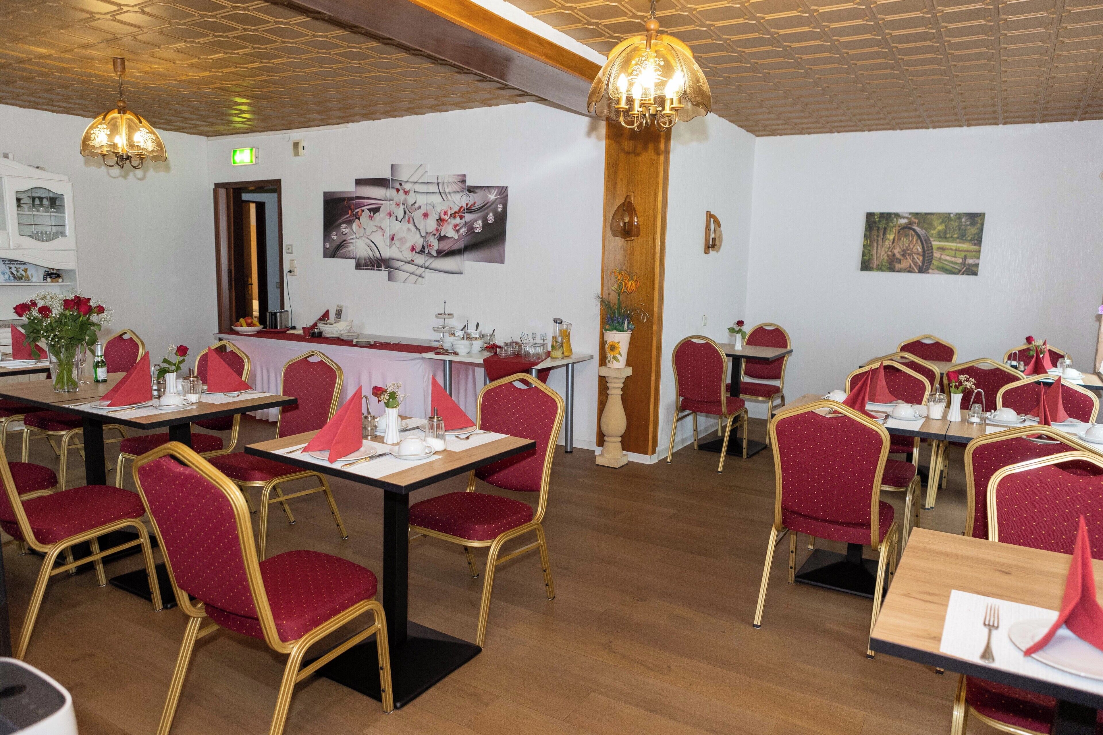 A restaurant with multiple tables and chairs, a wooden ceiling, and wall-mounted artwork.