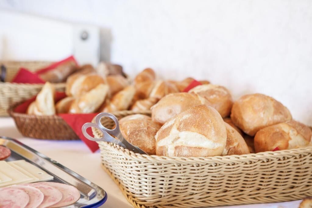A table with baskets of bread and a tray of sliced meats.