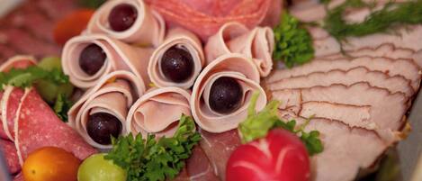 A charcuterie board with various meats, olives, and garnishes.