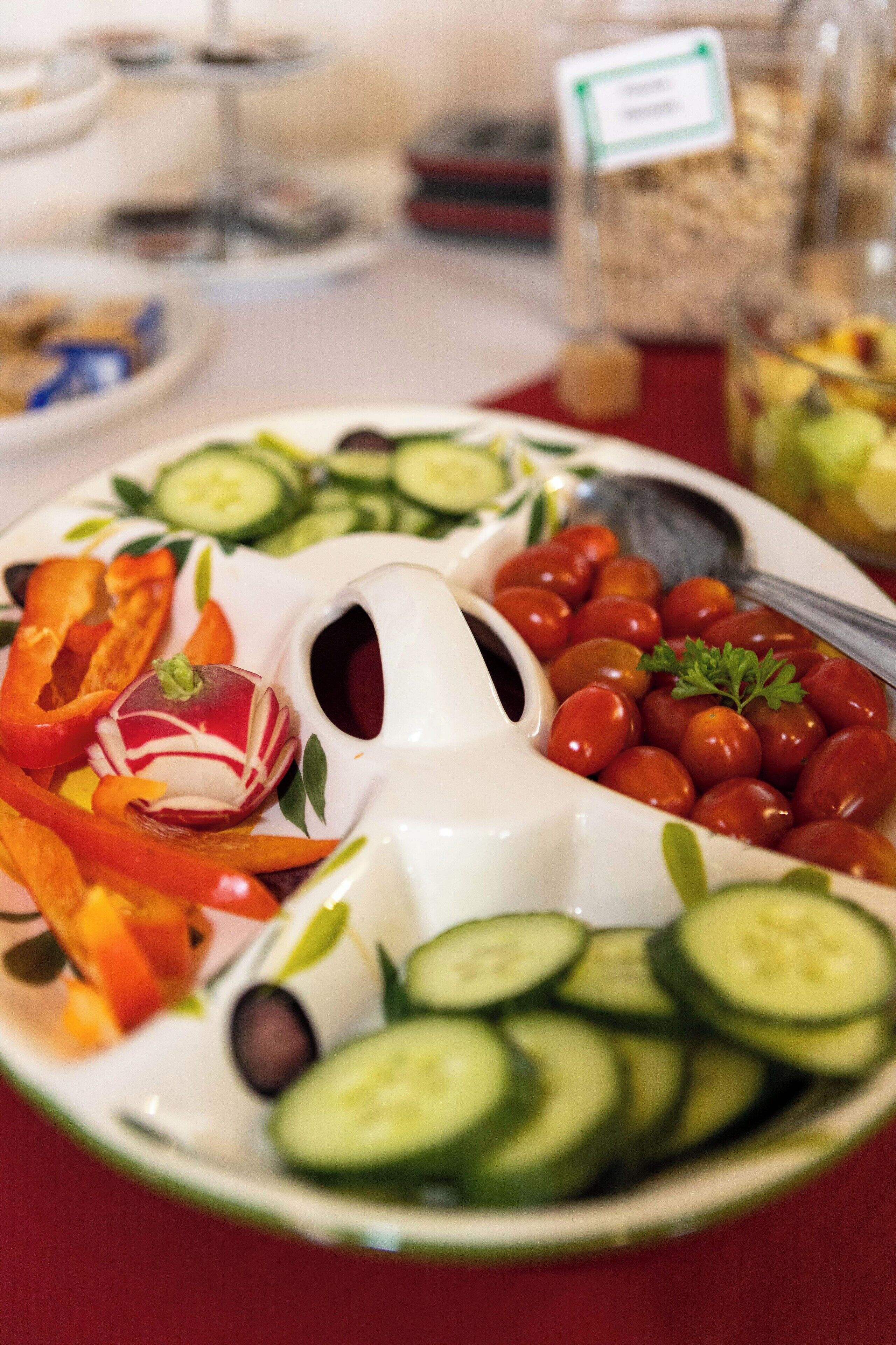 A platter of assorted vegetables including cucumbers, cherry tomatoes, and bell peppers.