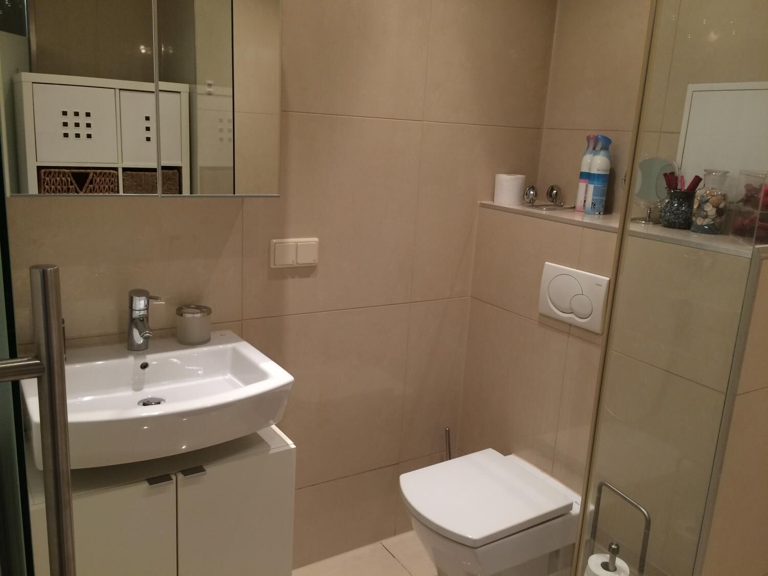 Een badkamer met een wit wastafel, toilet en spiegel.