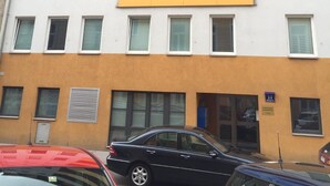 A multi-story building with balconies, a car parked in front, and a sign indicating the number 11. - Loft Apartment- Nähe Belvedere (Vienna)