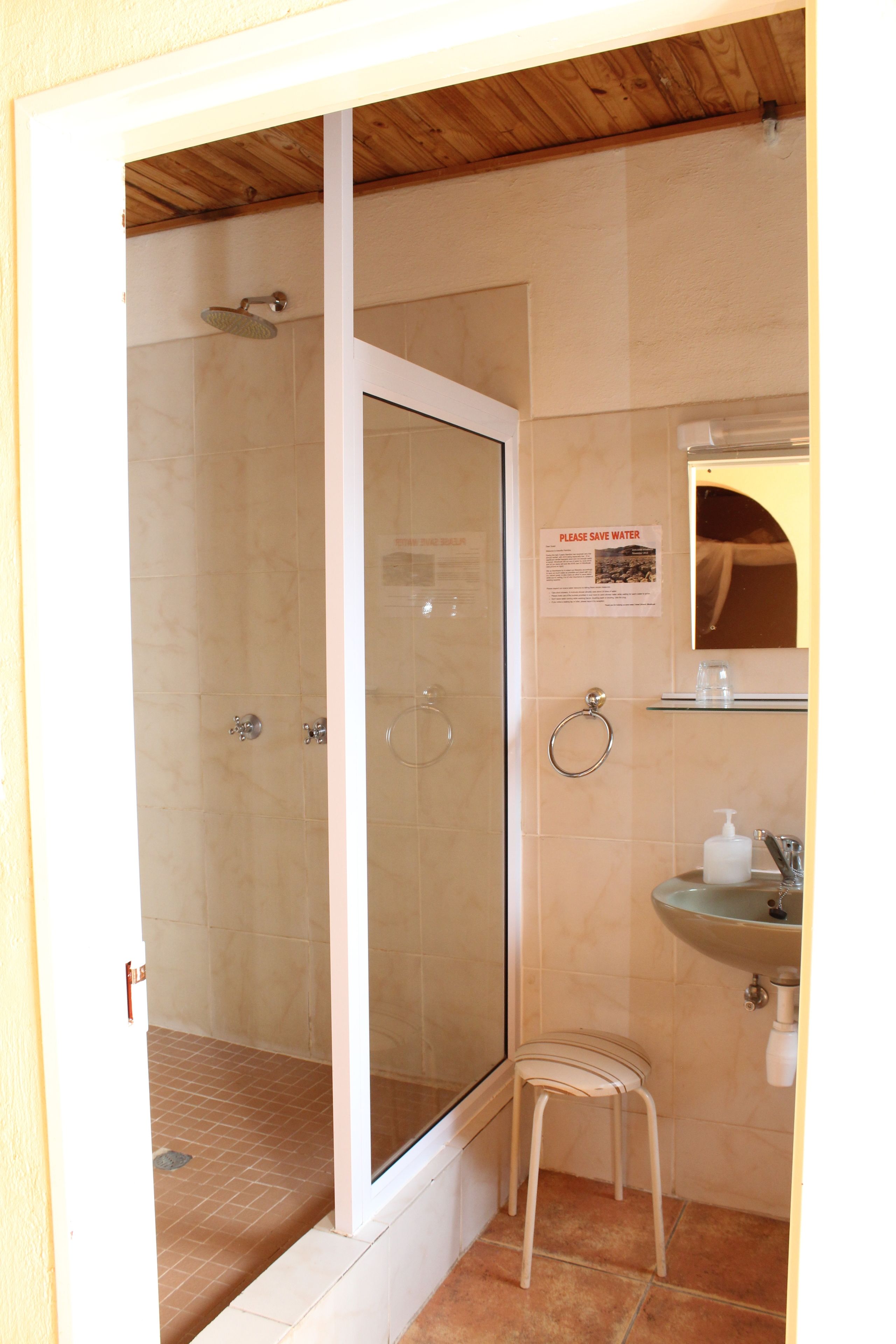 Un baño con ducha envuelta en vidrio, lavamanos e inodoro.