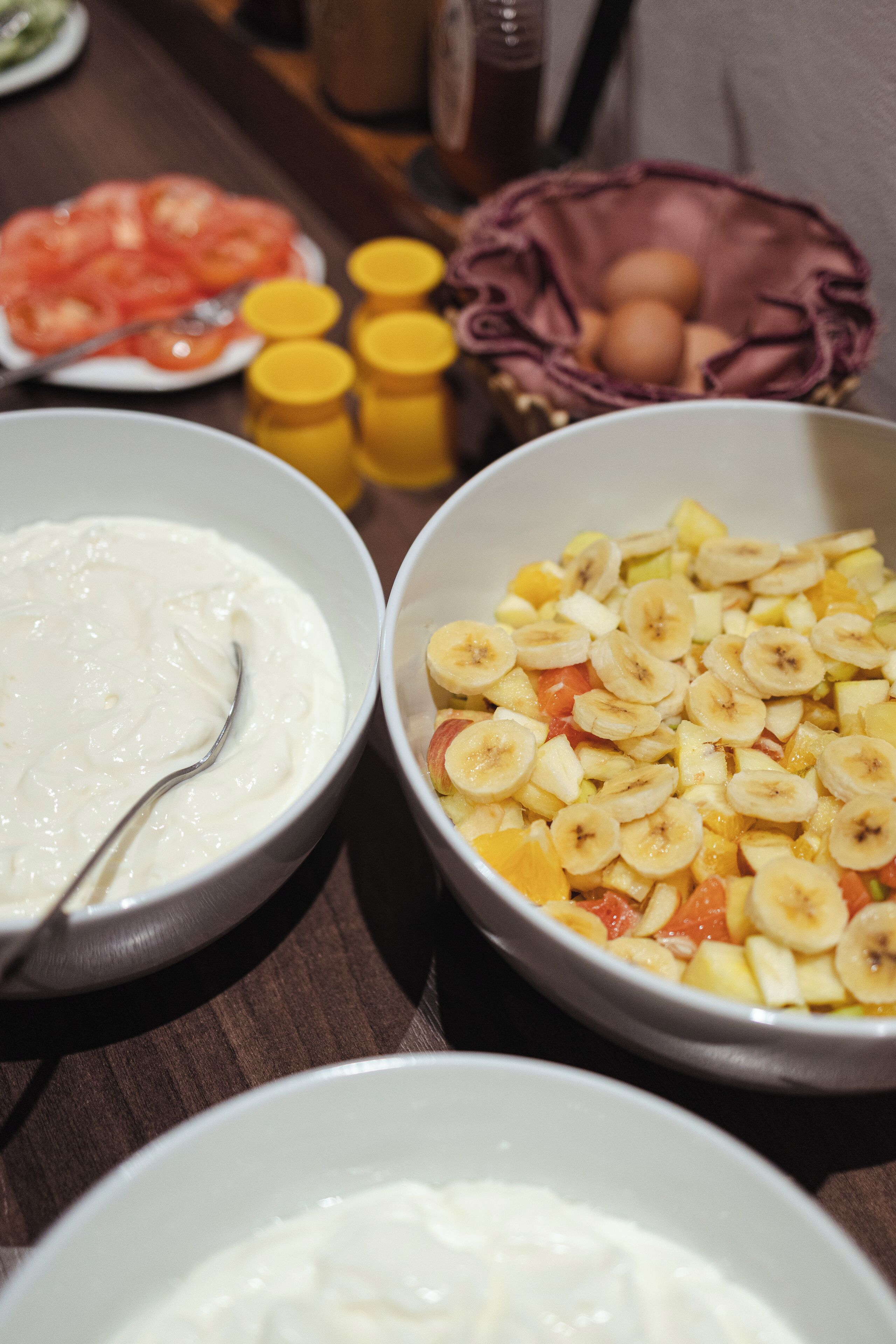 Una mesa con tazones de comida, incluyendo yogur y ensalada de frutas.