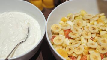 Una mesa con tazones de comida, incluyendo yogur y ensalada de frutas.