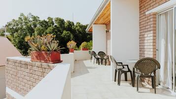 Un balcon agrémenté de plantes en pot, une table et des chaises.