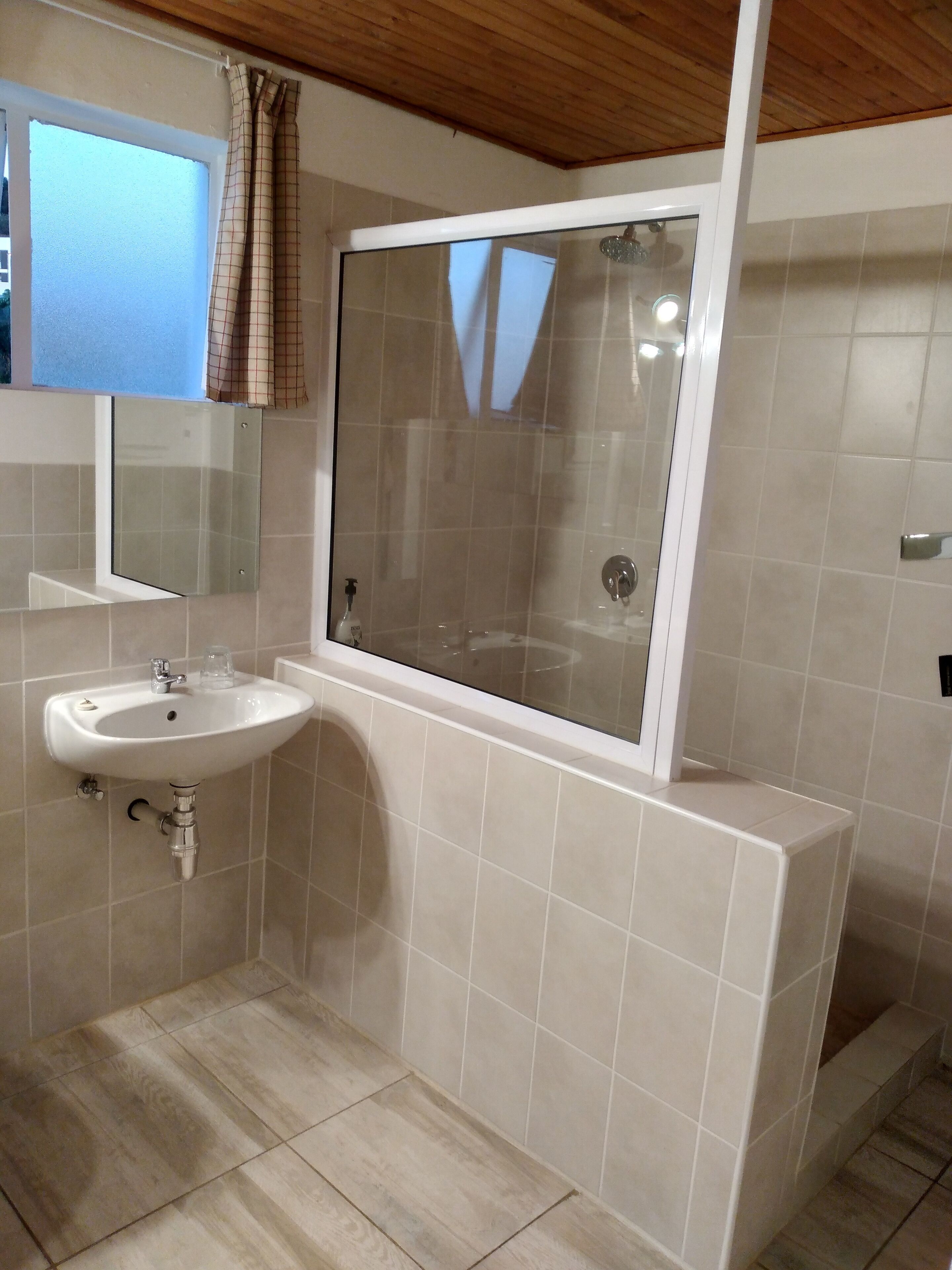 A bathroom with a sink, mirror, and shower.