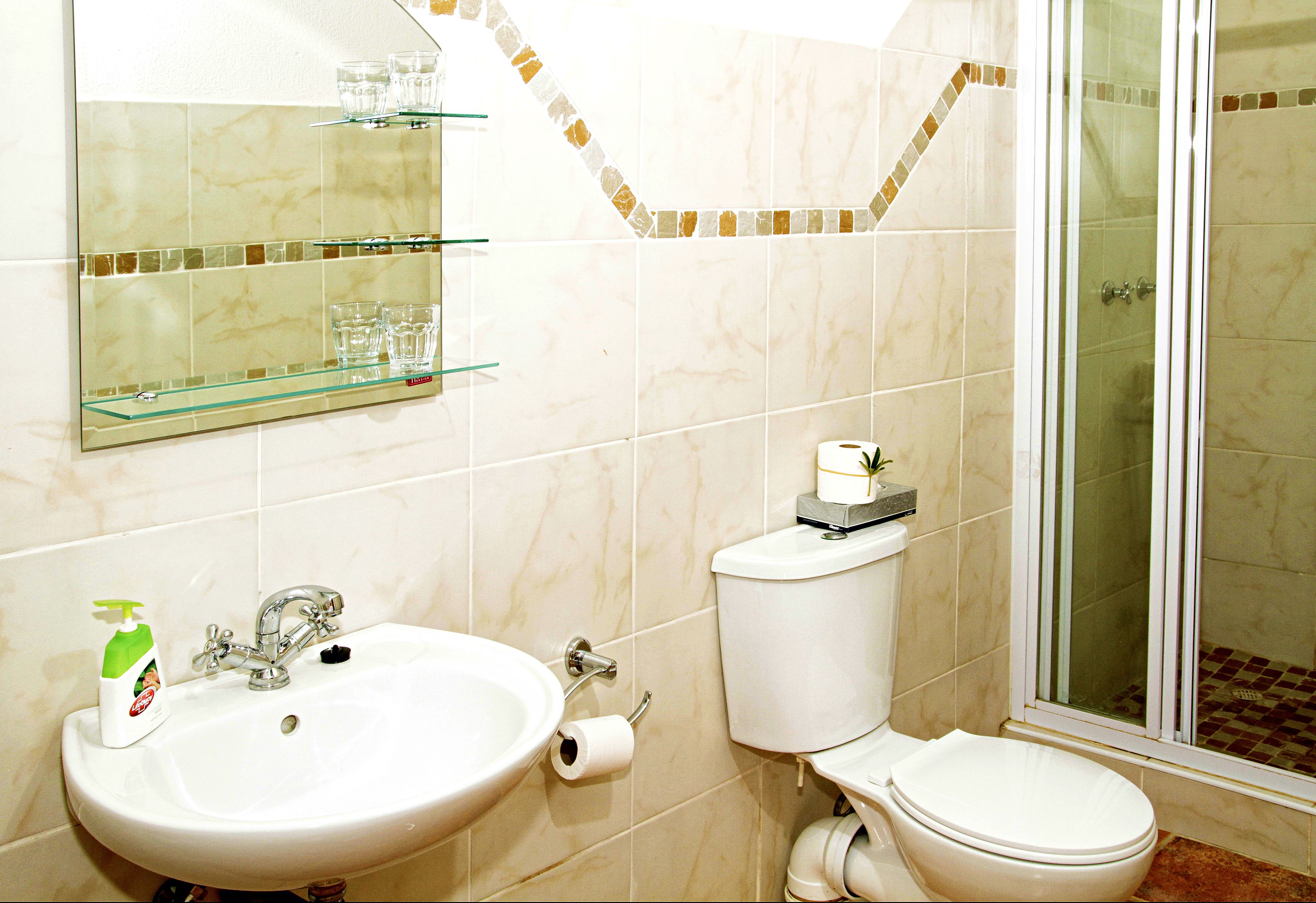 Ein Badezimmer mit Waschbecken, Toilette und Duschkabine aus Glas.