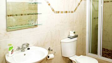 Ein Badezimmer mit Waschbecken, Toilette und Duschkabine aus Glas.