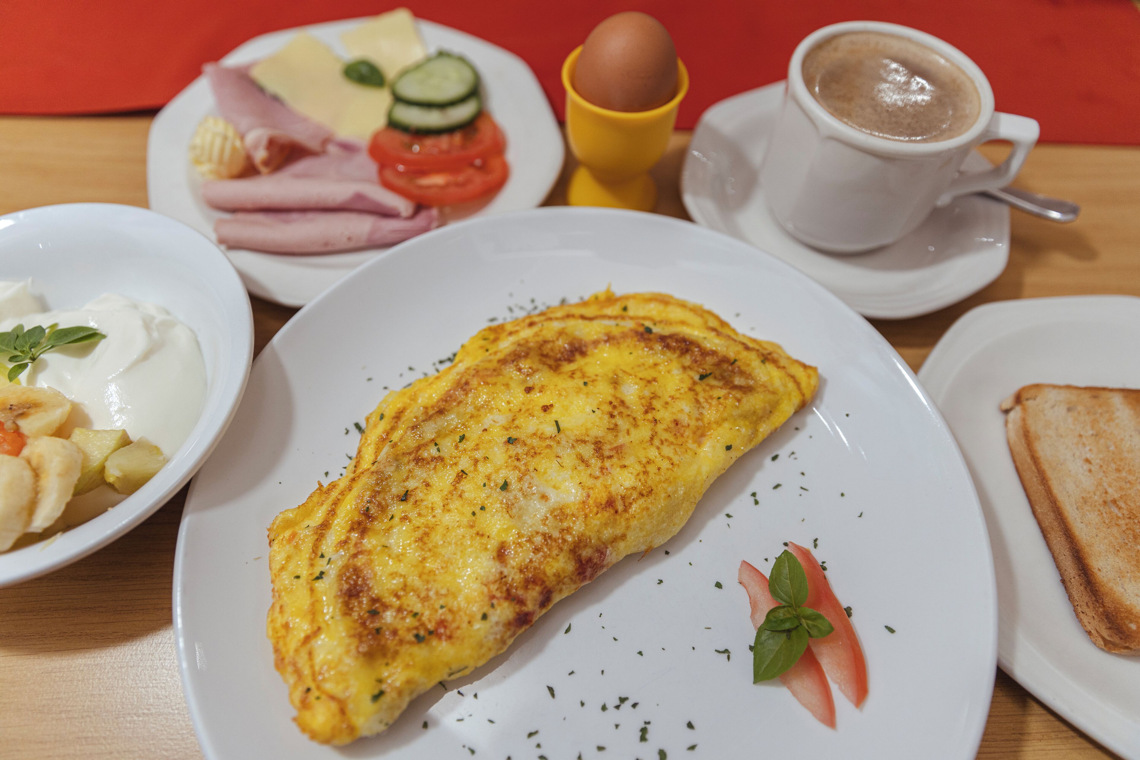 Une table dressée pour le petit-déjeuner avec une omelette, des toasts, du café et divers accompagnements.
