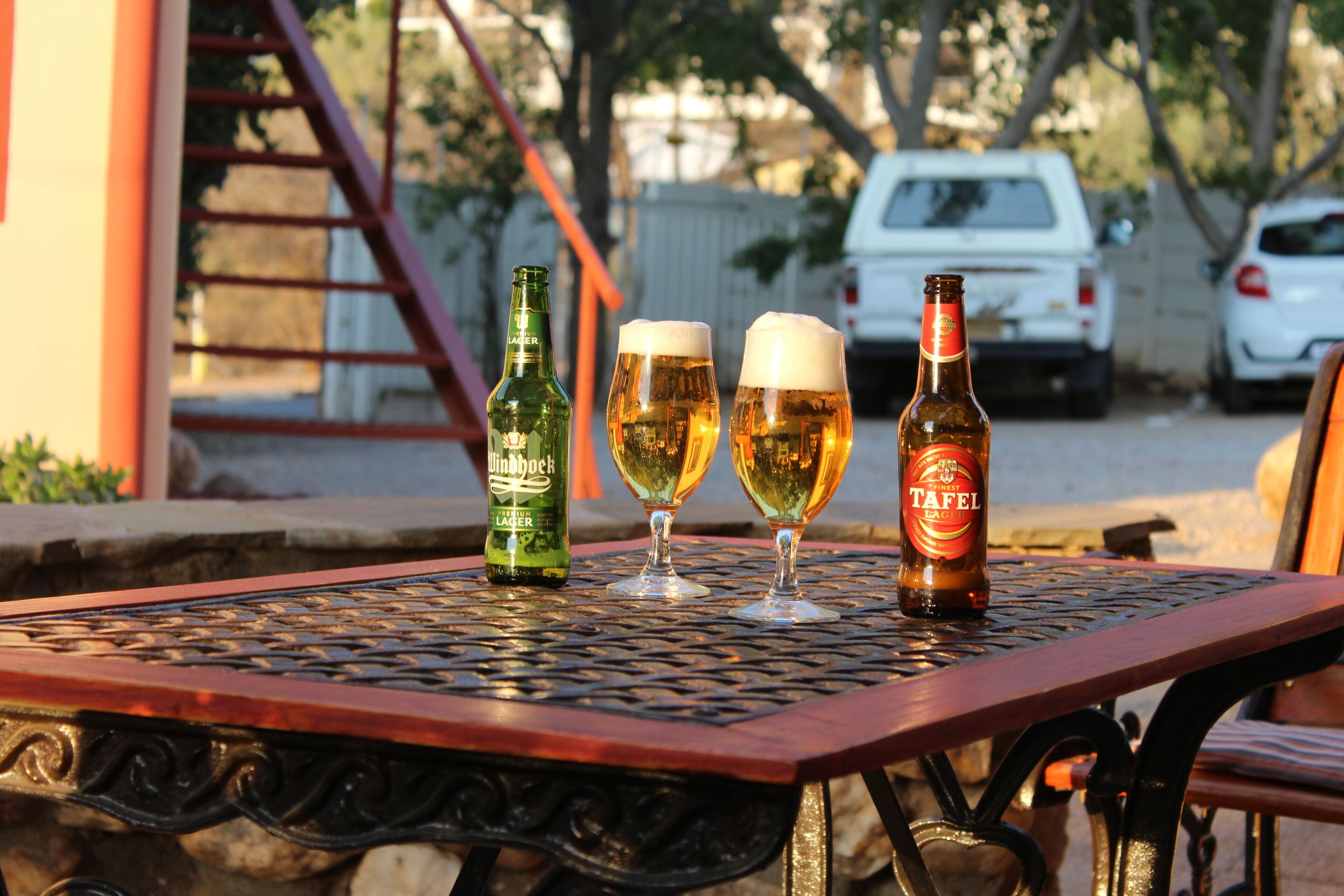 A table with two beer glasses and two bottles of beer.