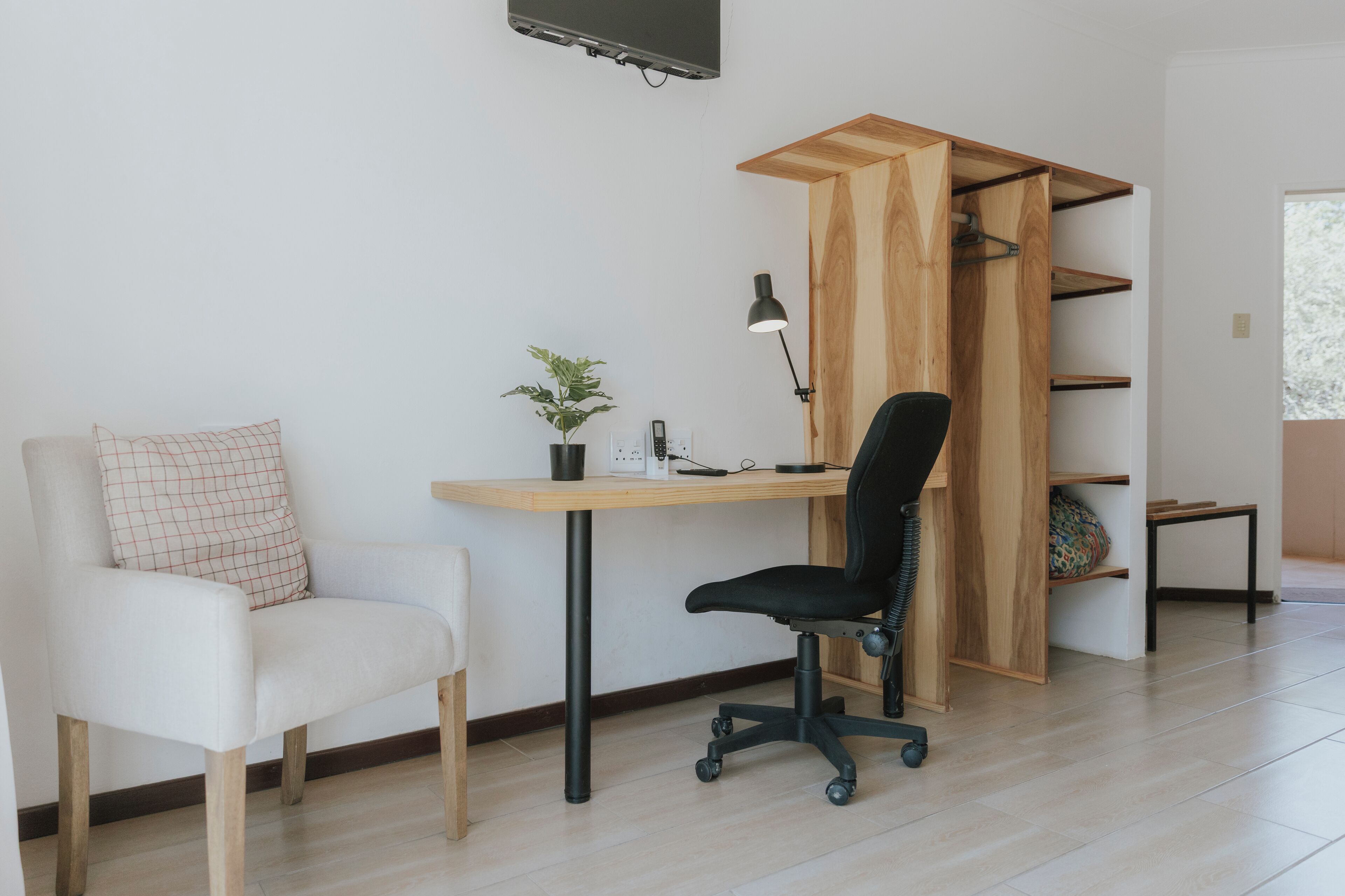 A modern office space with a desk, chair, and shelving unit.