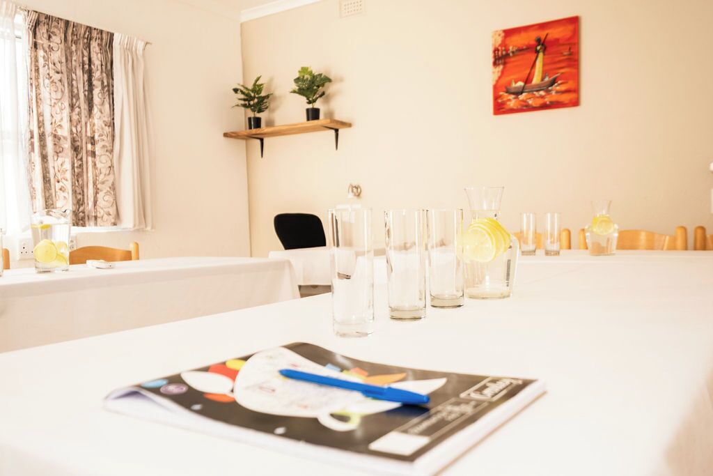 A conference room with a white table, glassware, and a magazine.