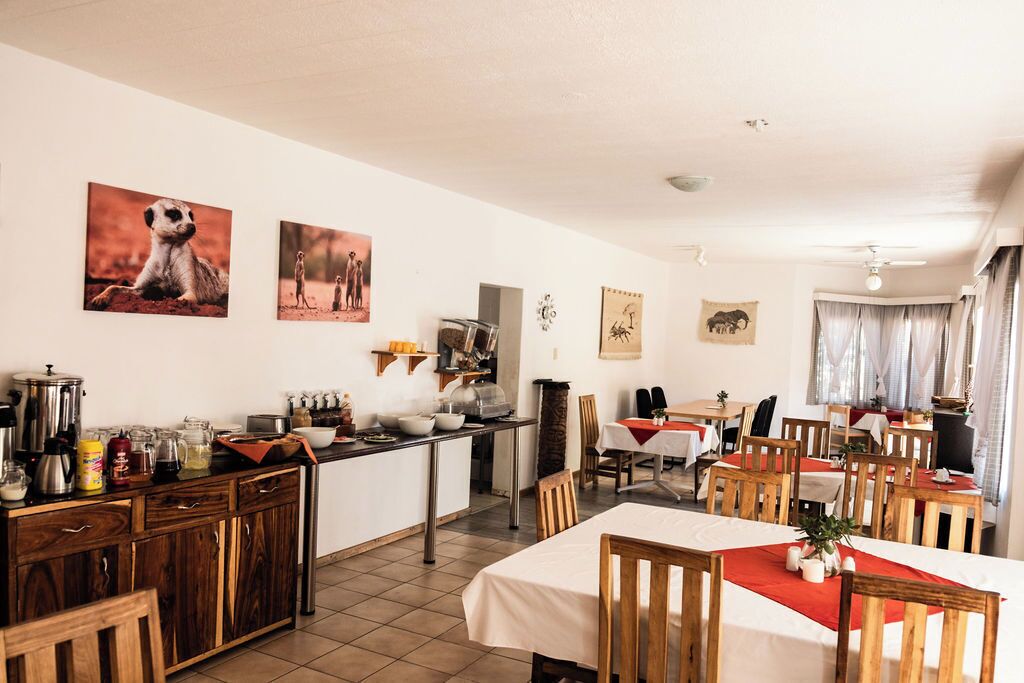 Un comedor con sillas y mesas de madera, una encimera de cocina con varios objetos y decoración en la pared, incluyendo estampados de animales.