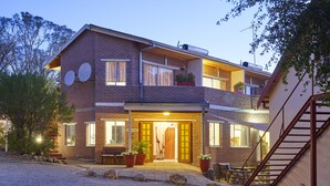 A two-story brick house with a balcony, a staircase, and a gravel driveway. - Hotel Uhland (Windhoek)