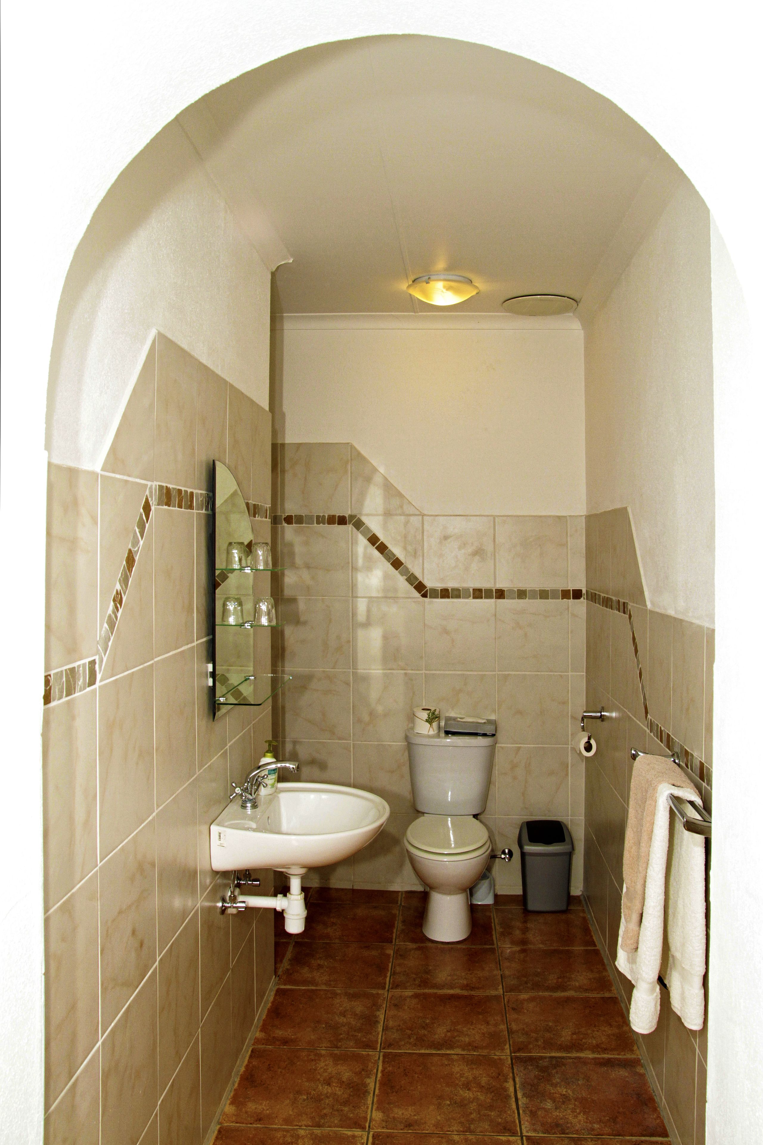 Un baño con lavamanos, inodoro y espejo.