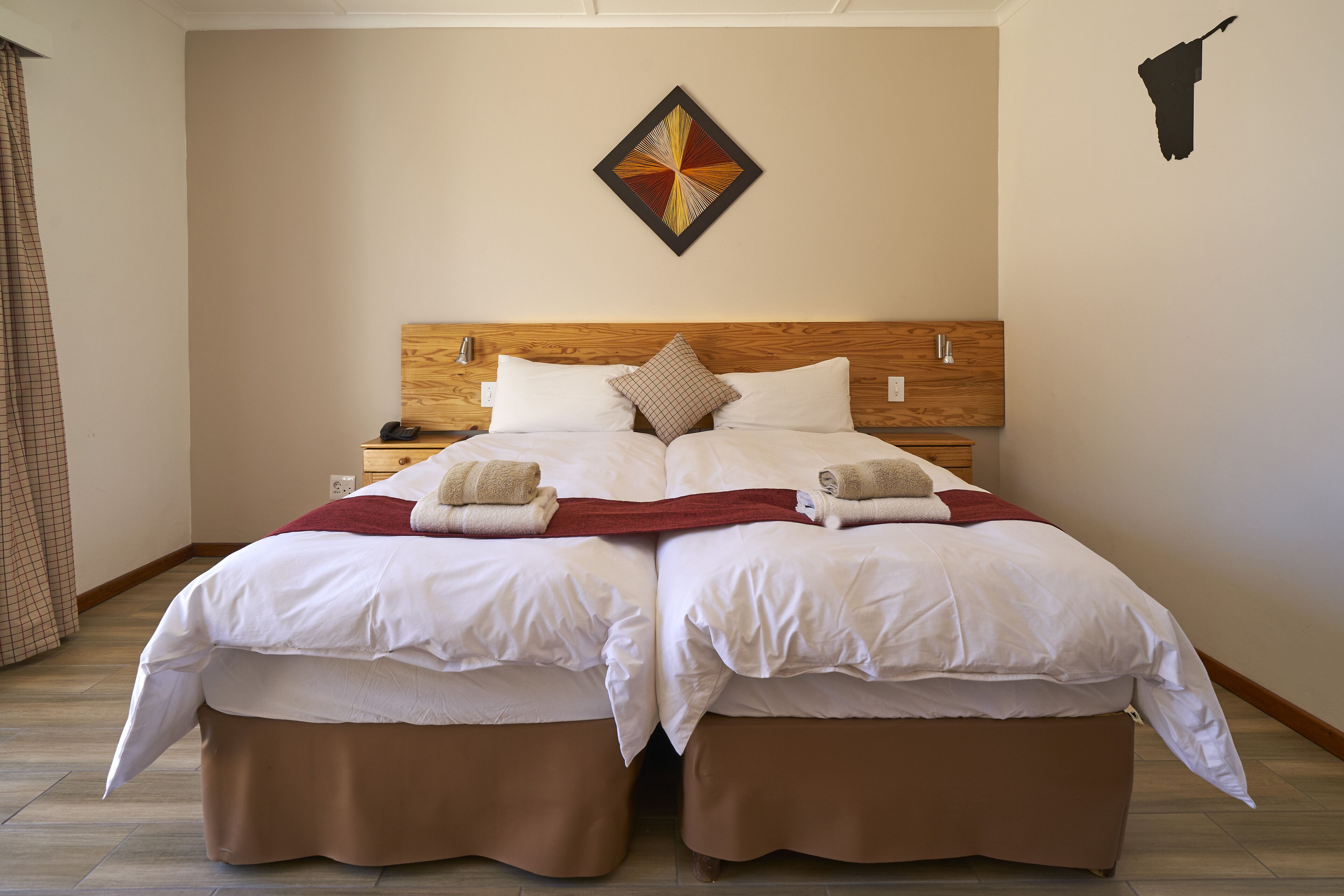 A double bed with a wooden headboard, two bedside tables, and a decorative wall piece.