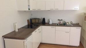 A compact kitchen with white cabinets, a microwave, a kettle, and a coffee maker. - Apartment- Schottenfeldgasse (Vienna)
