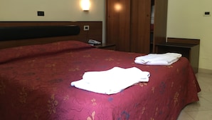 A hotel room with a bed, a wardrobe, a bedside table, and a wall-mounted light. - Hotel Positano (Rome)